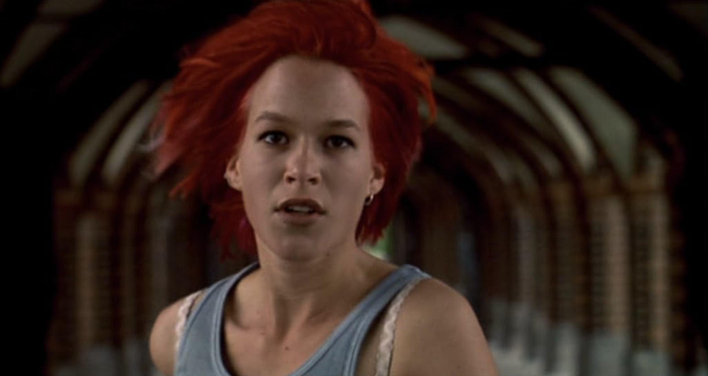 Close up image of a woman with bright red hair runing through a tunnel.