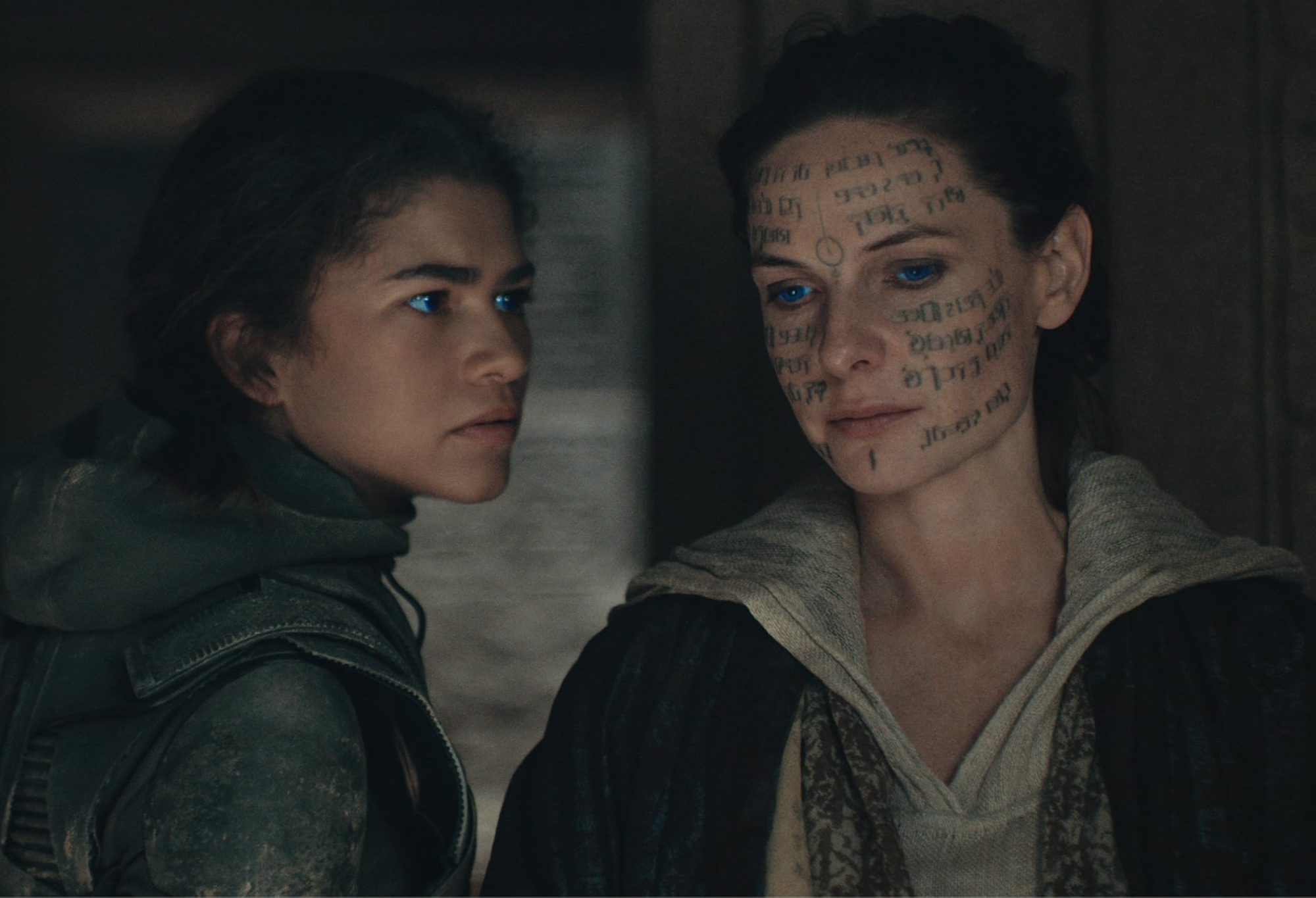 A young woman glares at an older woman with face tattoos.